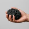 Pieza de roca de lava negra talla S-M sostenida en la mano para ver su tamaño real