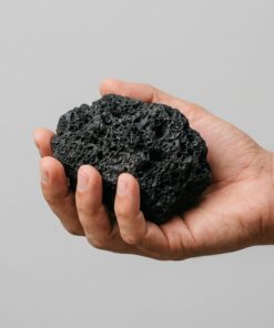 Pieza de roca de lava negra talla S-M sostenida en la mano para ver su tamaño real
