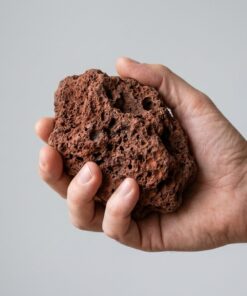 Pieza de roca de lava roja talla S-M sostenida en la mano para ver su tamaño real